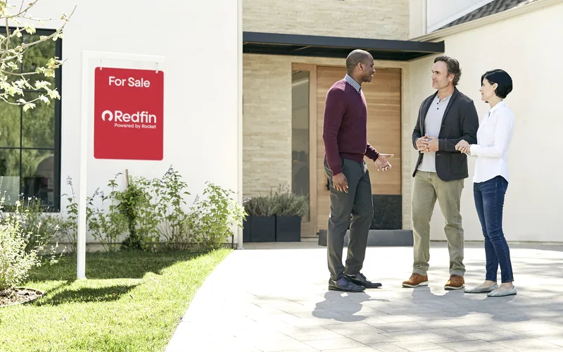 Buyers touring a newly built home with a Redfin for sale sign in the front yard